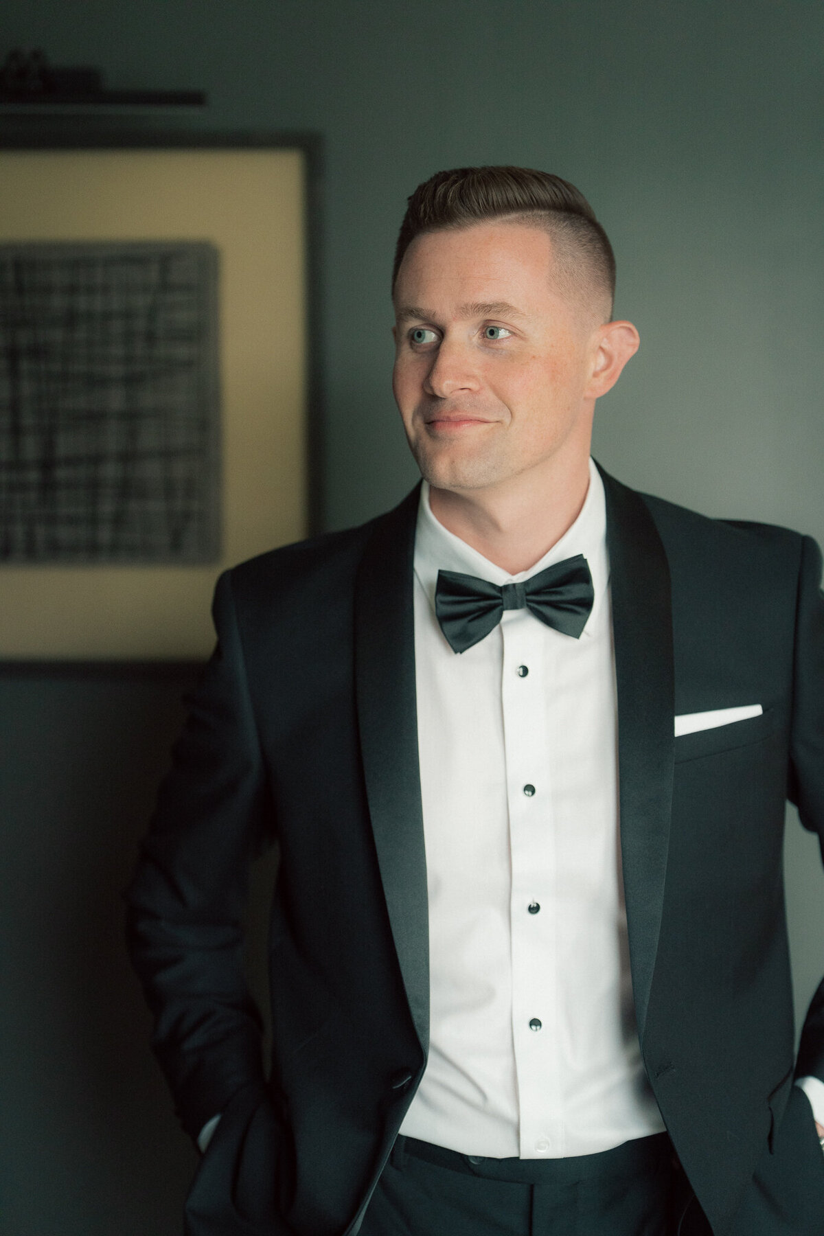 Groom portrait in black tuxedo with bow tie before wedding ceremony