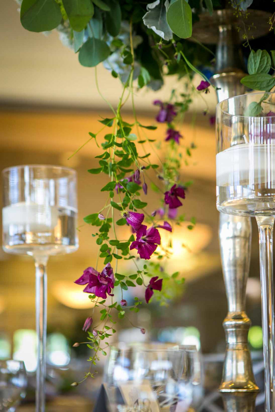 purple clematis vines trailing off of a tall centerpiece with floating candle