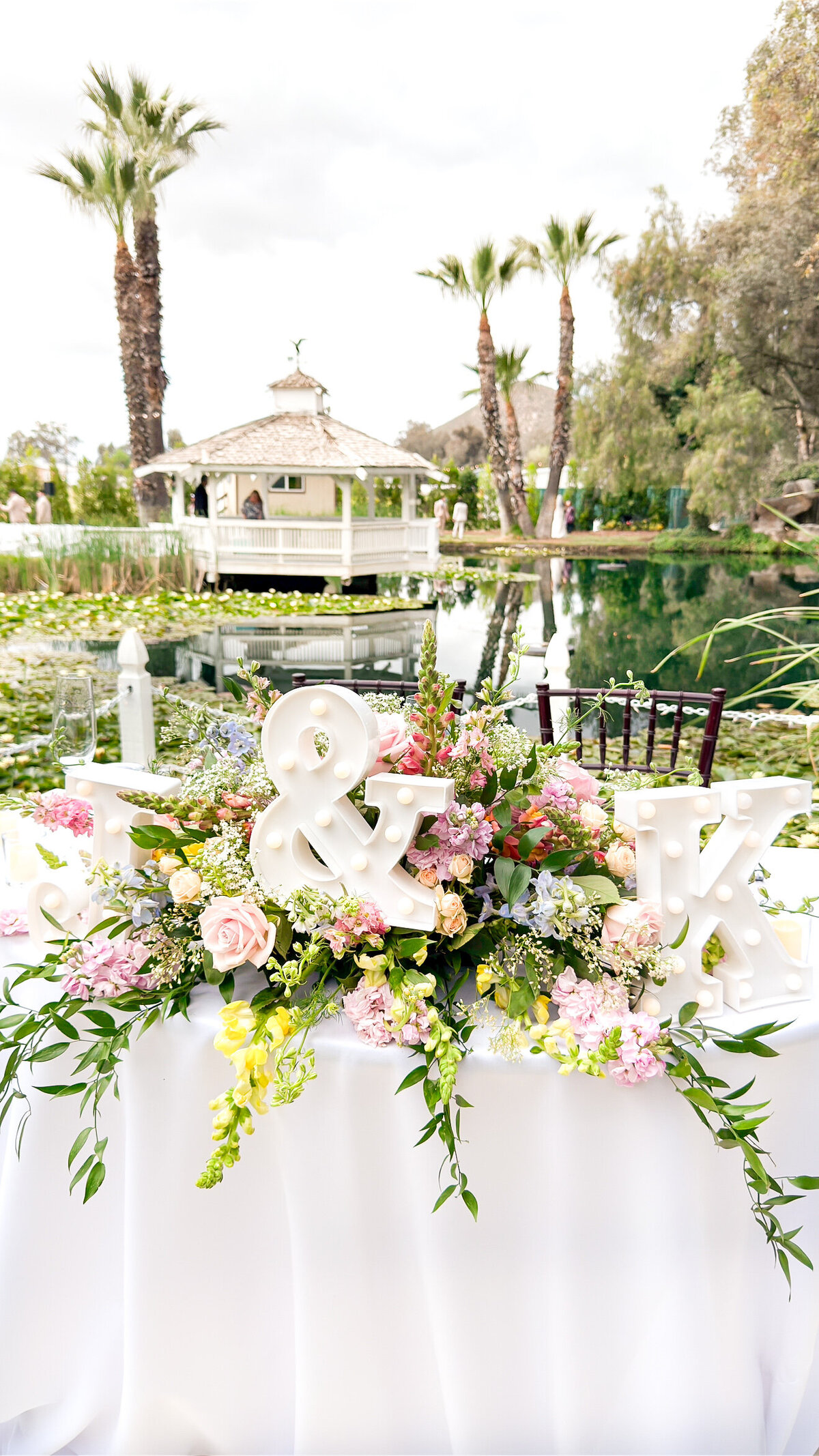 White sweetheart table with colorful floral centerpiece in front of the Wedgewood Ceremony Gazebo at The Orchard Wedgewood Weddings Venue in Riverside.