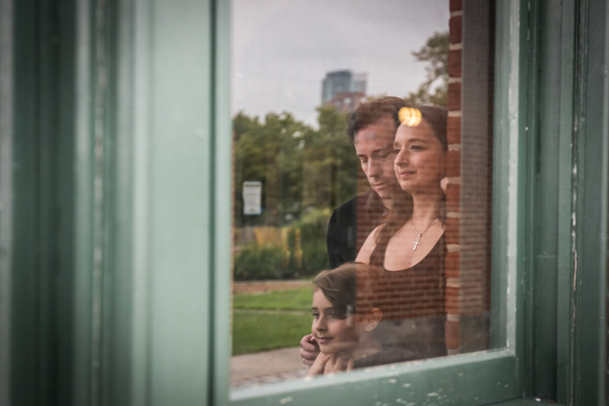 The reflection of two parents and a child in a window