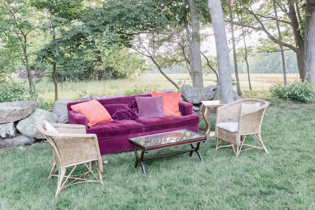 A maroon sofa and chairs make up an area to rest during the wedding reception