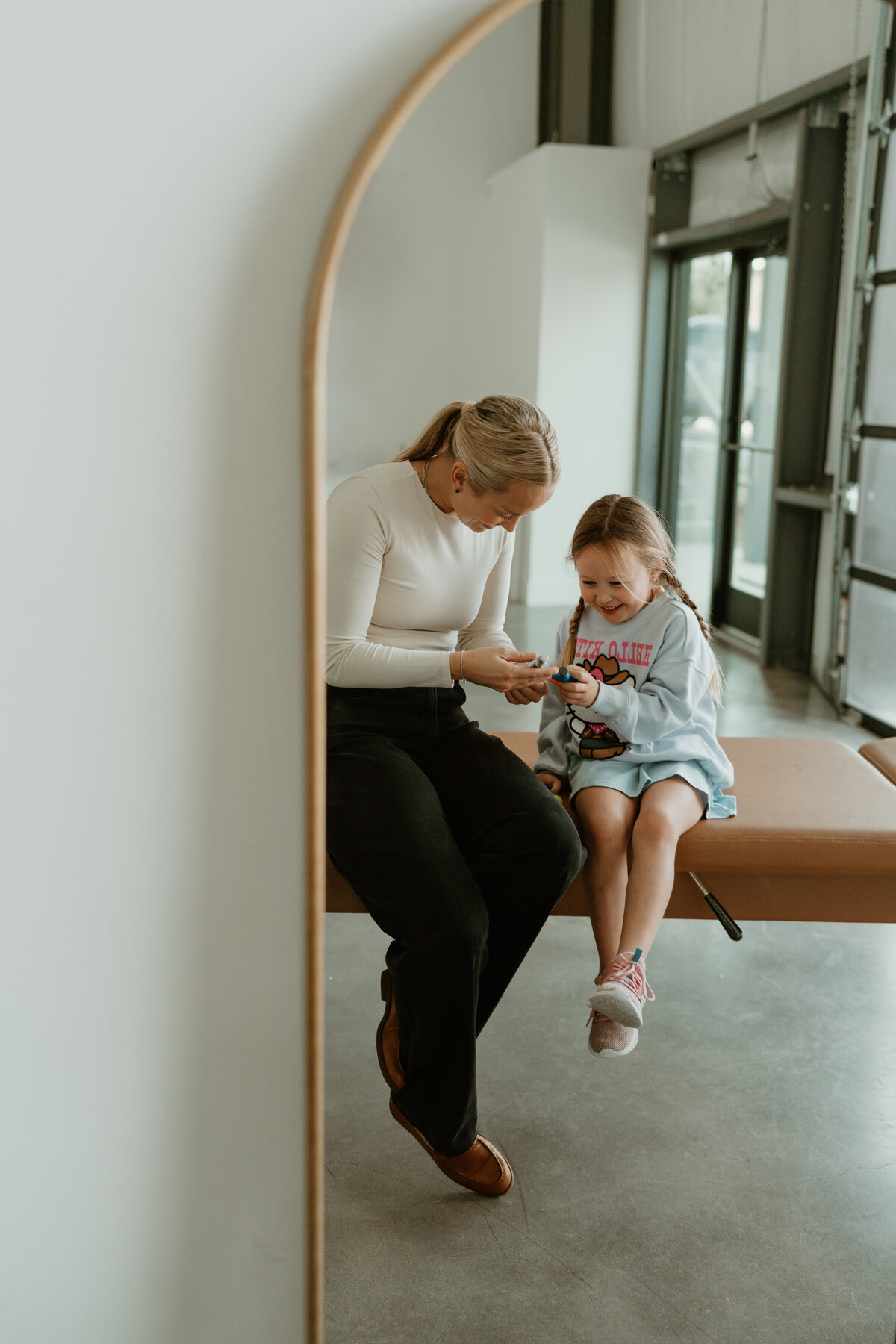 woman and young girl  smiling looking at chiropractic tools 