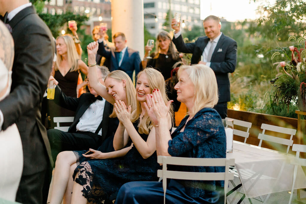 wedding guests sitting and standing behind them clapping for them