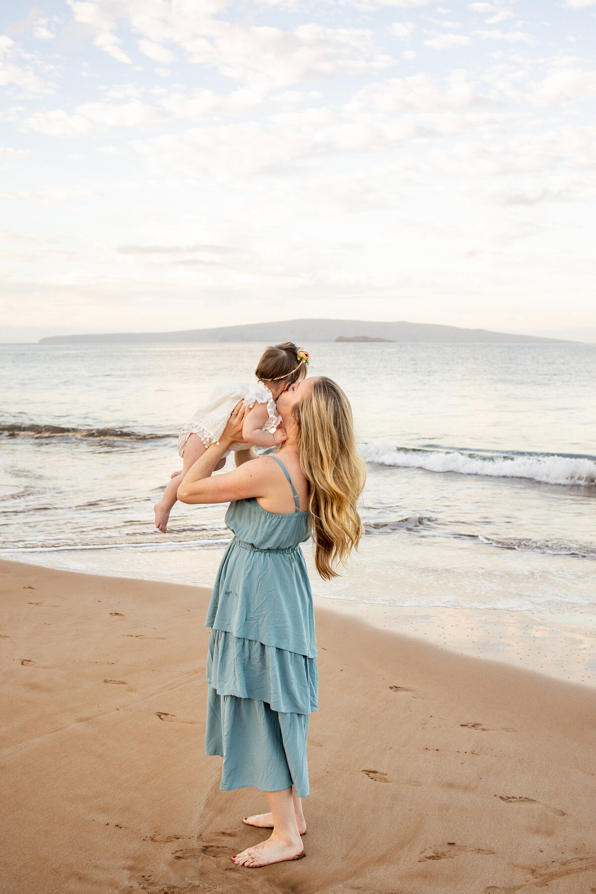 Maui Family Photographers capture mother kissing daughter's cheek while lifting her up