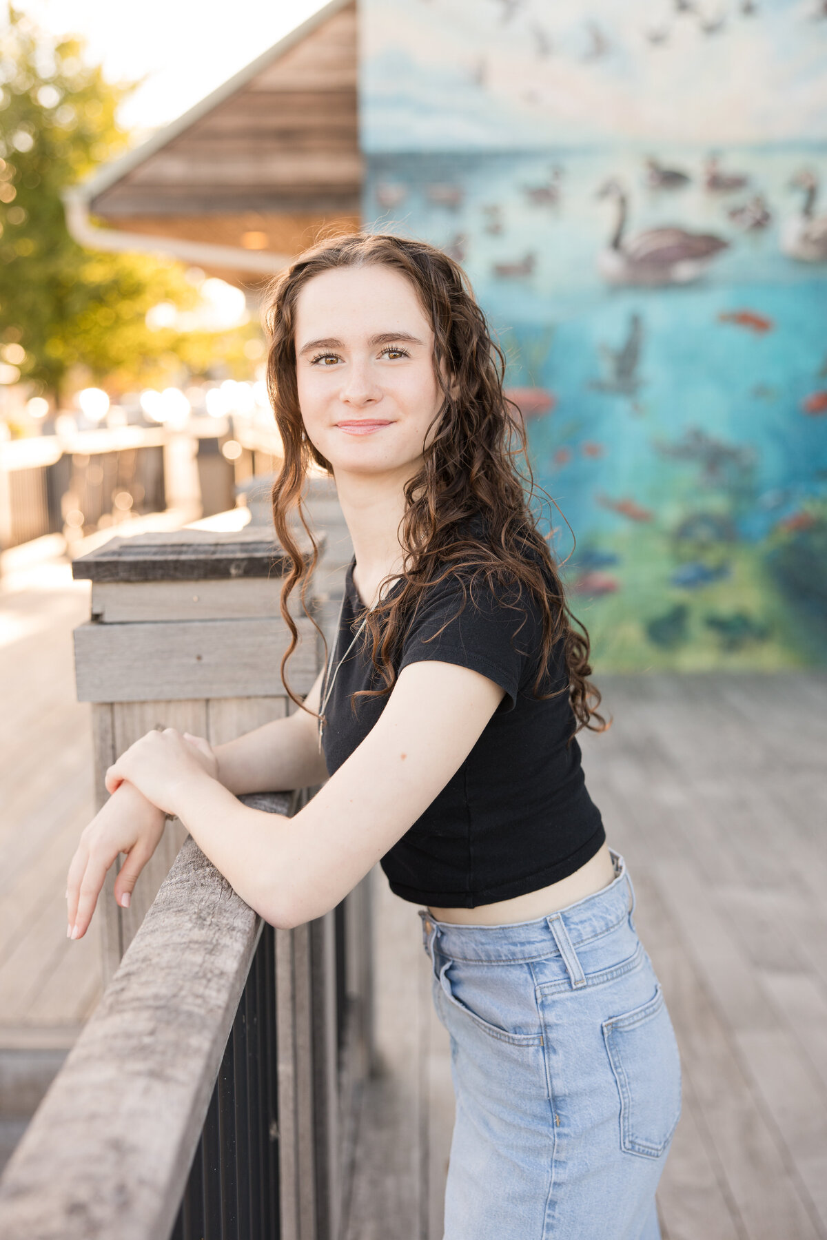 Senior girl leaning against a rail smiling at the camera