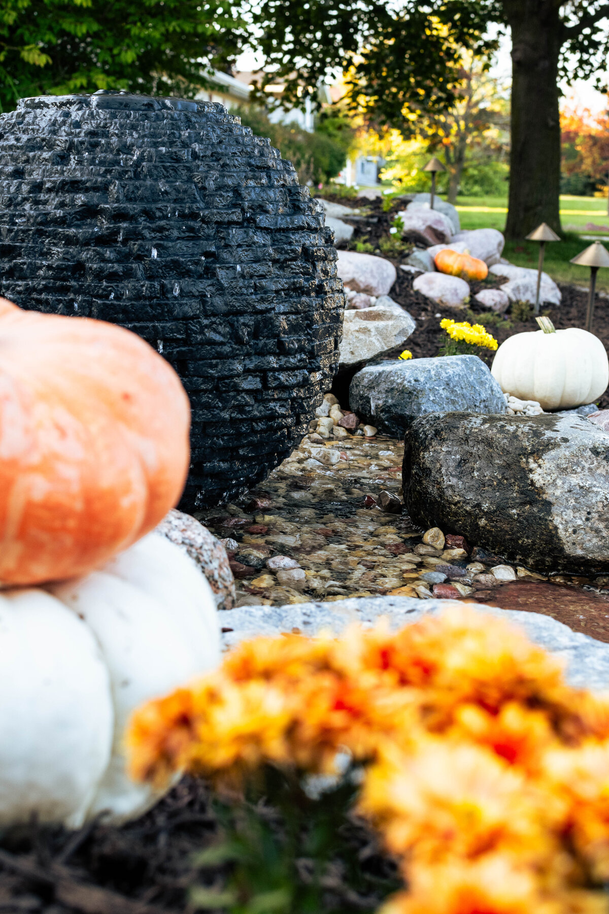 Stacked Slate Sphere fountain surrounded by pumpkins and mums for fall decoration