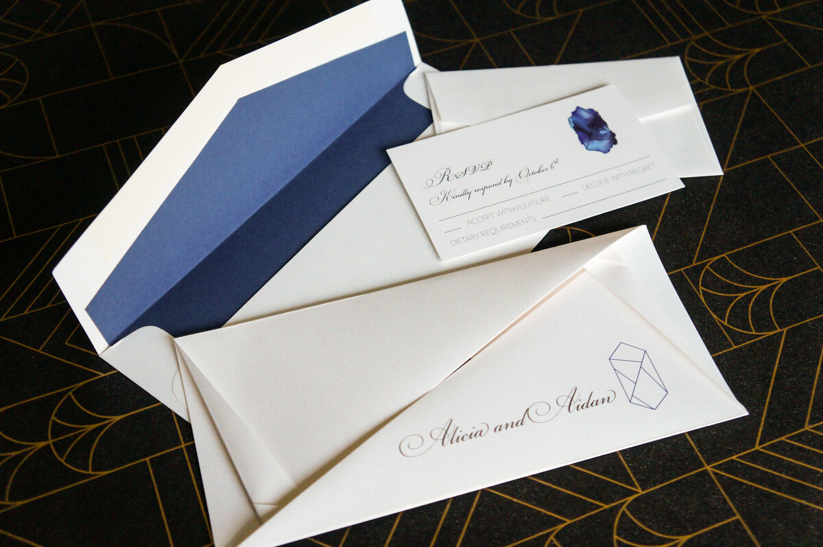 Folded origami wedding invitation with blue sapphire graphic and blue and white envelope