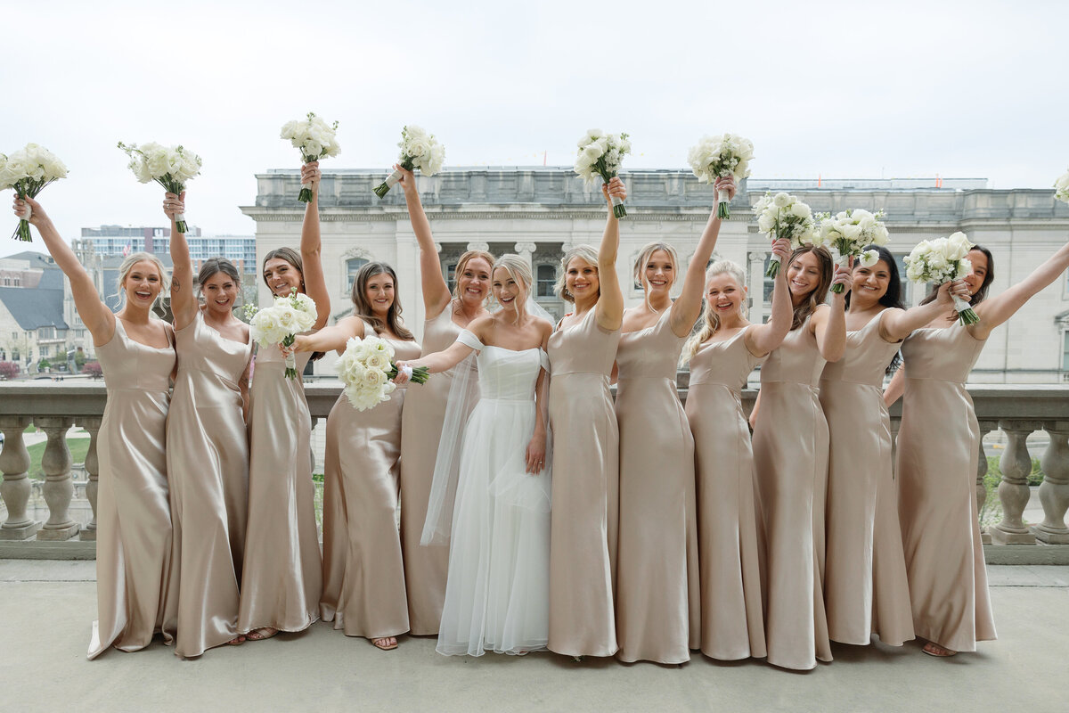 A joyful moment with the bridal party cheering on the iconic balcony of The Memorial Union, with Lake Mendota providing a stunning backdrop.