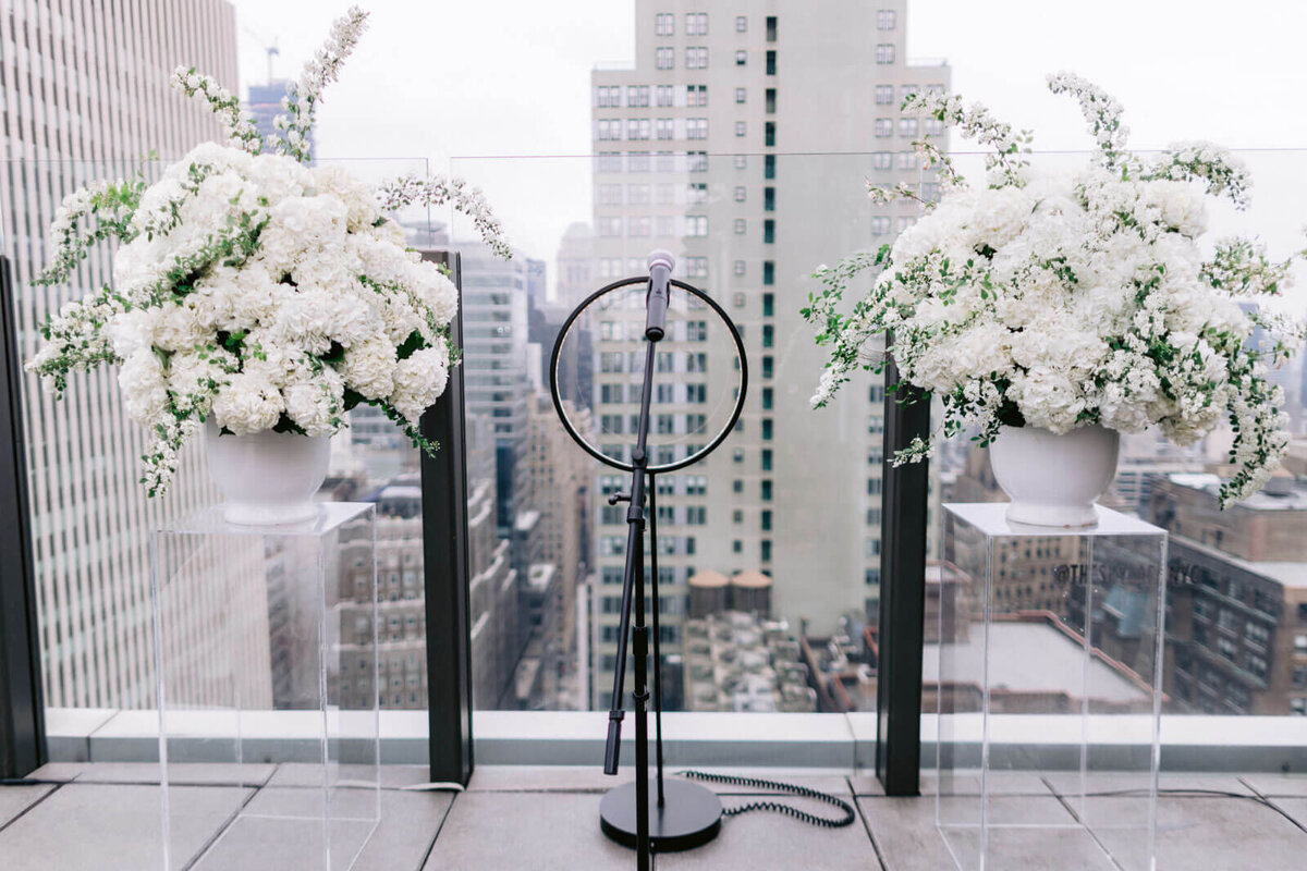 A ring light with white flowers on both sides, overlooking buildings in The Skylark, New York. Wedding Image by Jenny Fu Studio