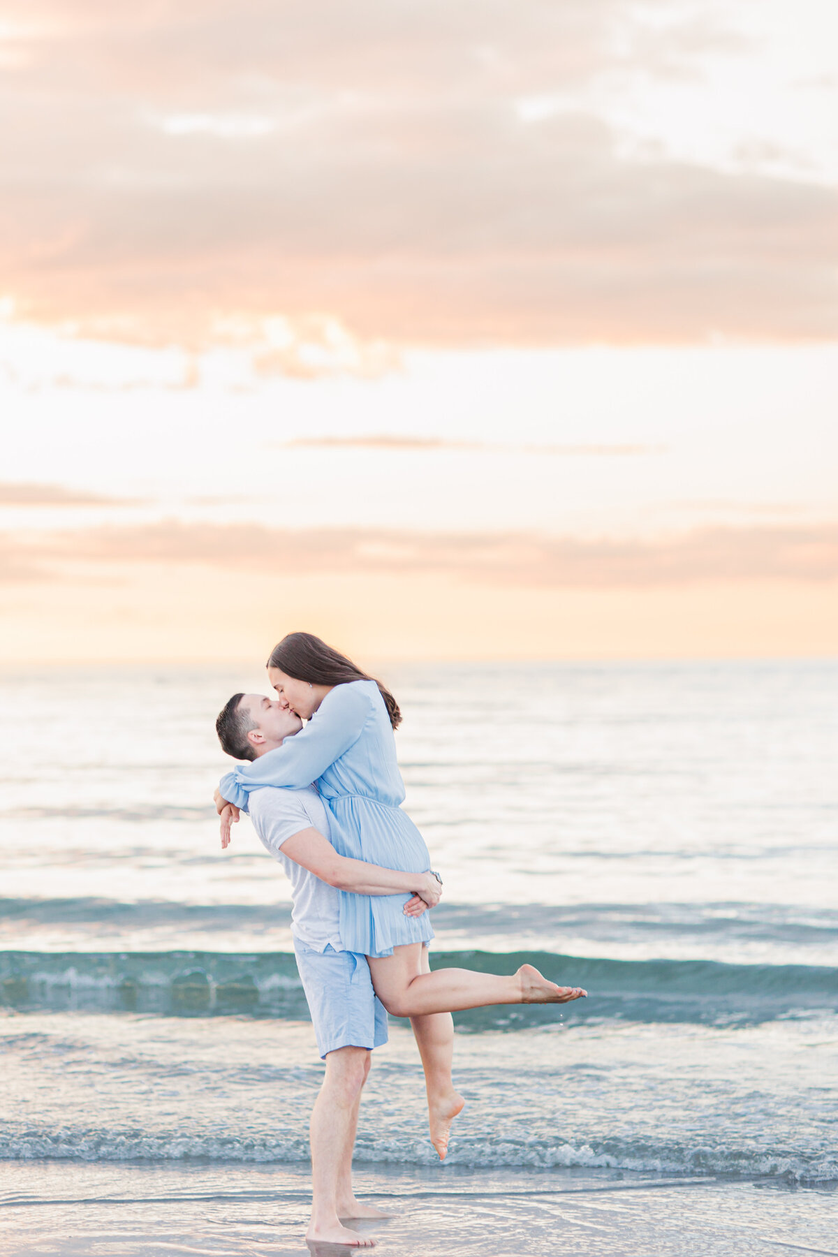Man picking up and kissing a woman representing MA beach engagement photography