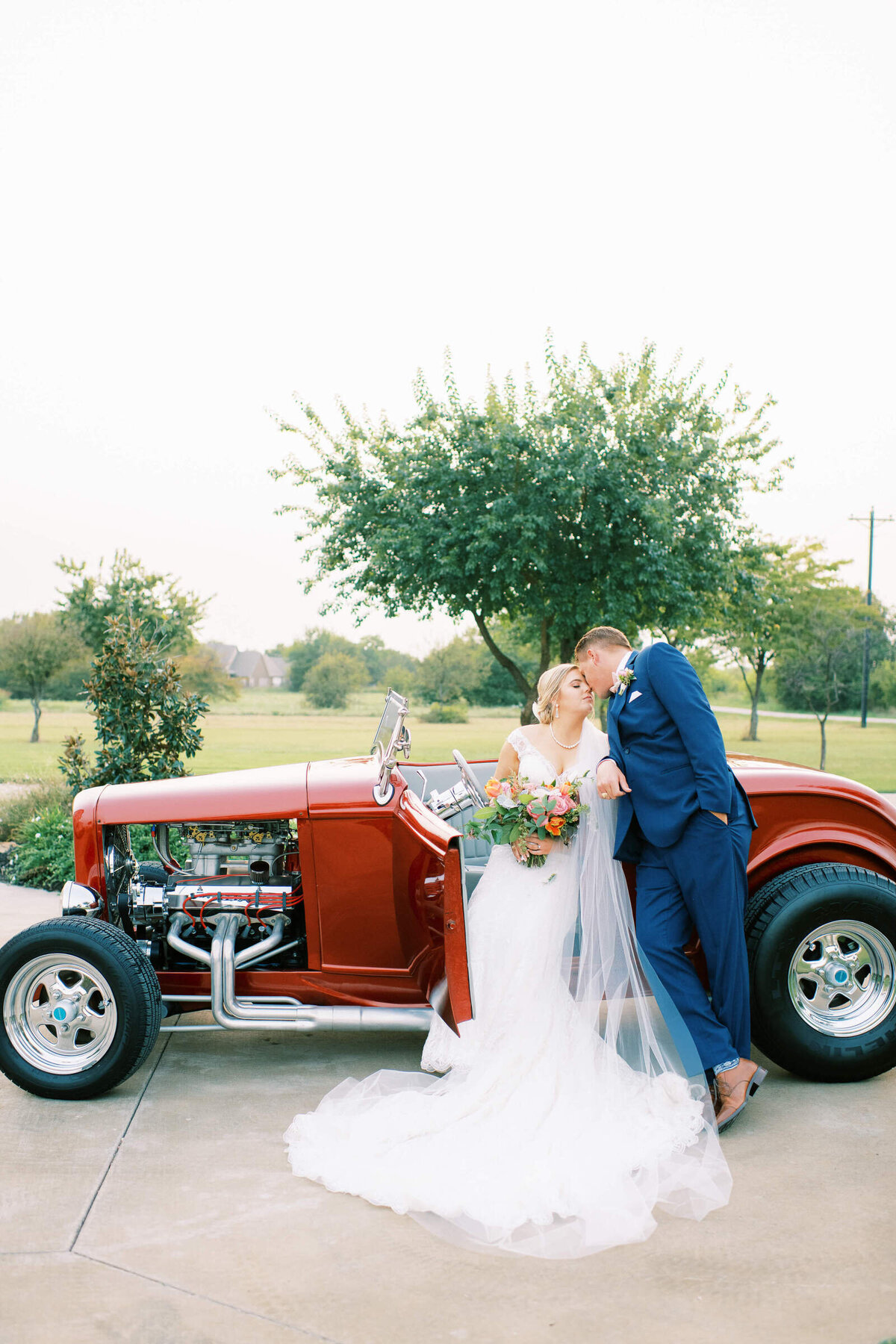 Bride and groom kiss in fancy old getaway car