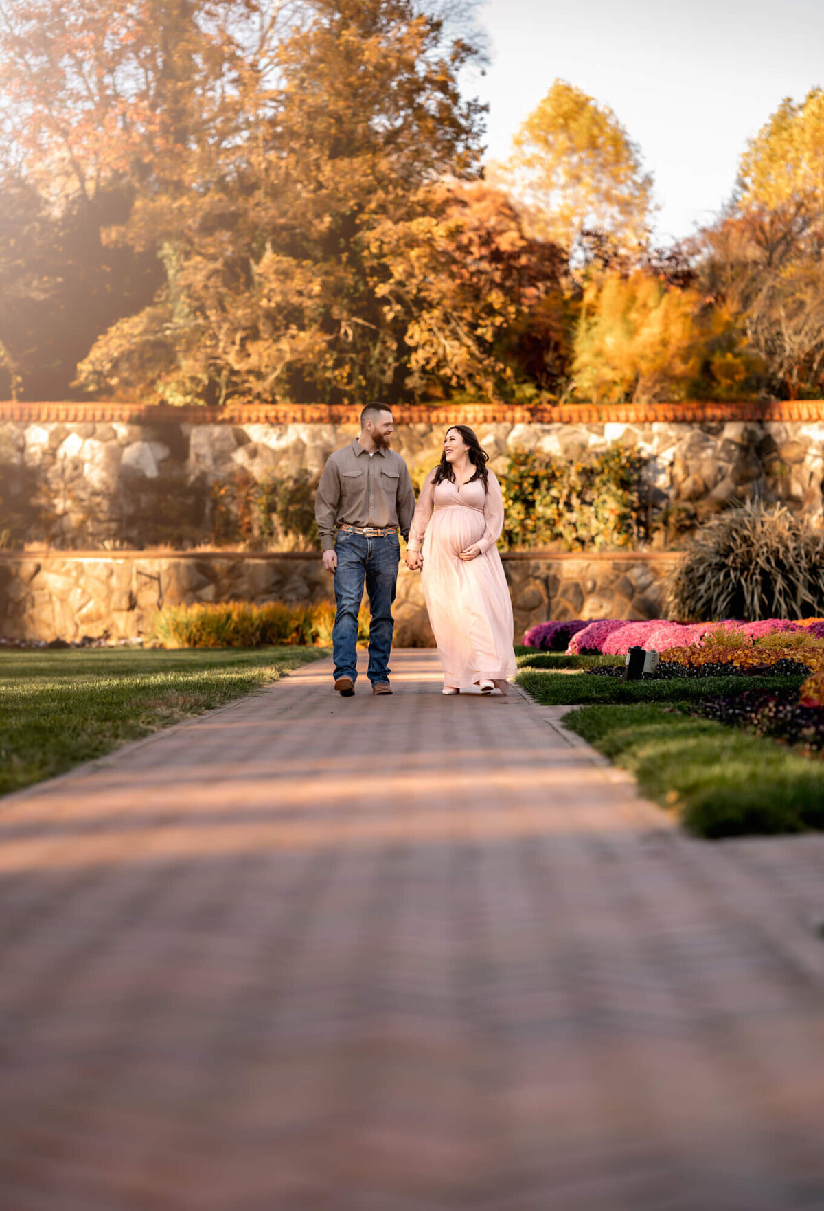 Sun rays light up a couple as they walk along a sidewalk holding hands