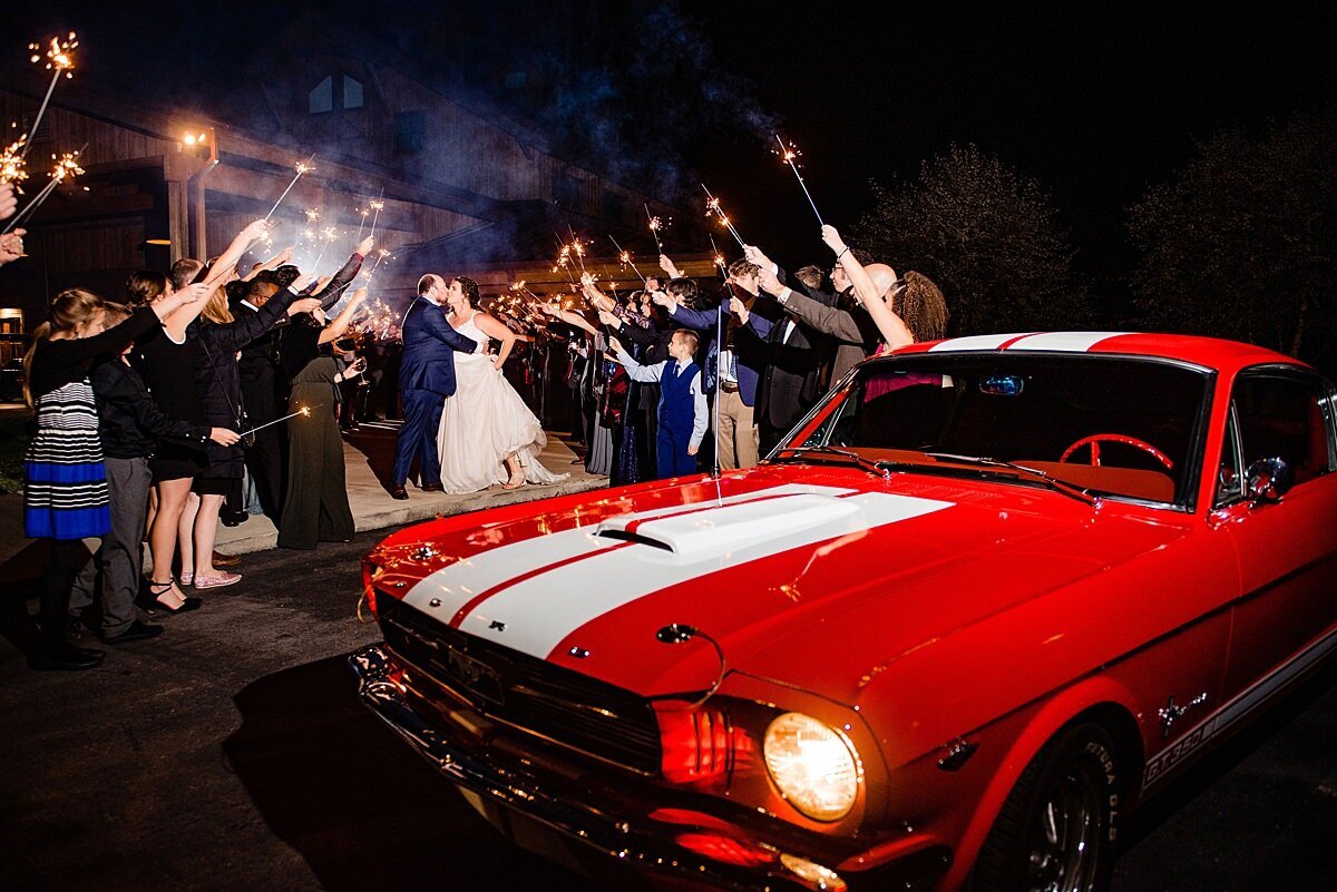 red and white ford mustang getaway car for bride and groom leaving wedding reception to sparkler exit.