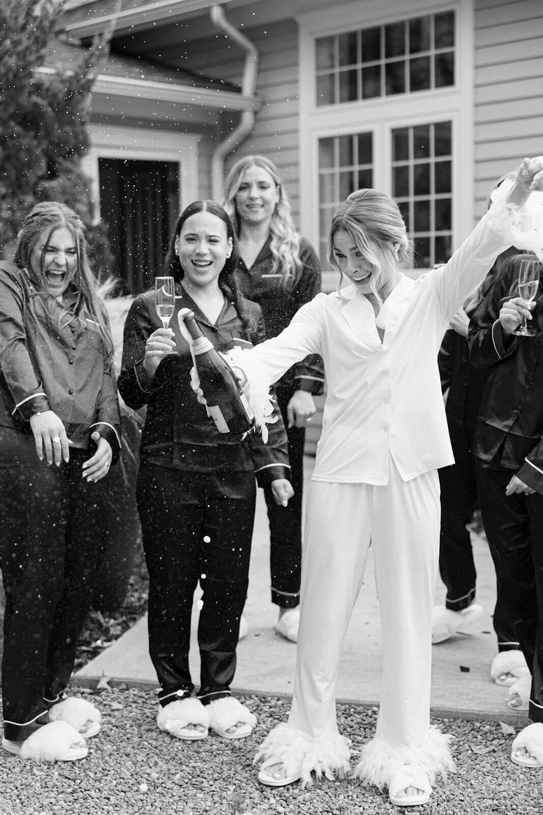 Bride popping champagne surrounded by bridesmaids