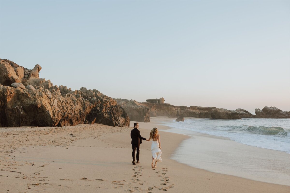 bride and groom running down a beach