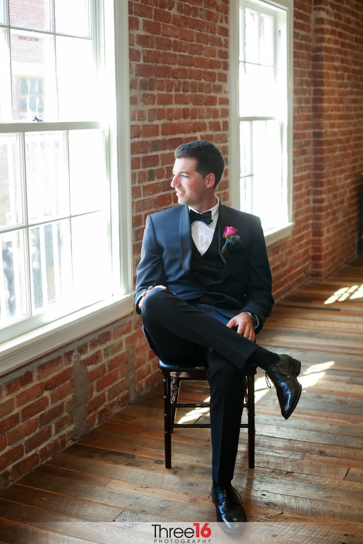 Groom sitting in a chair looking out the window prior to the ceremony