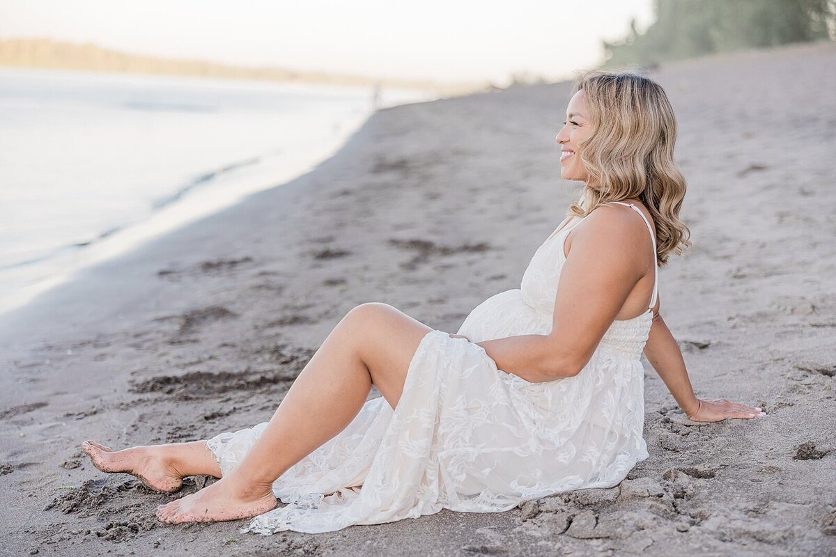 pregnant mom profile sitting on sandy beach in Portland, Oregon