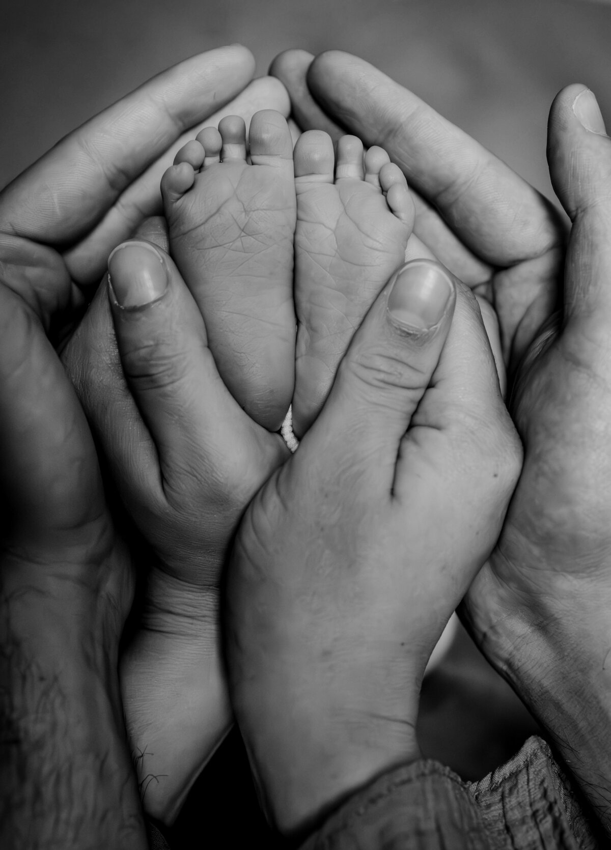 papa en mama hebben hun handen om de voetjes van de baby