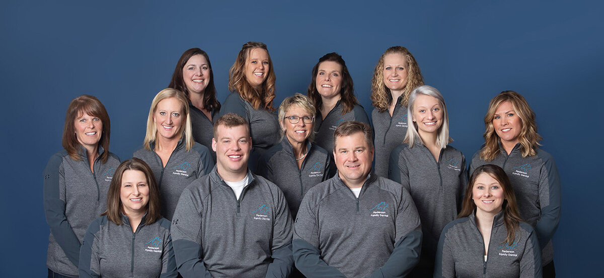 Team studio image of Pederson Family Dental blue backdrop.