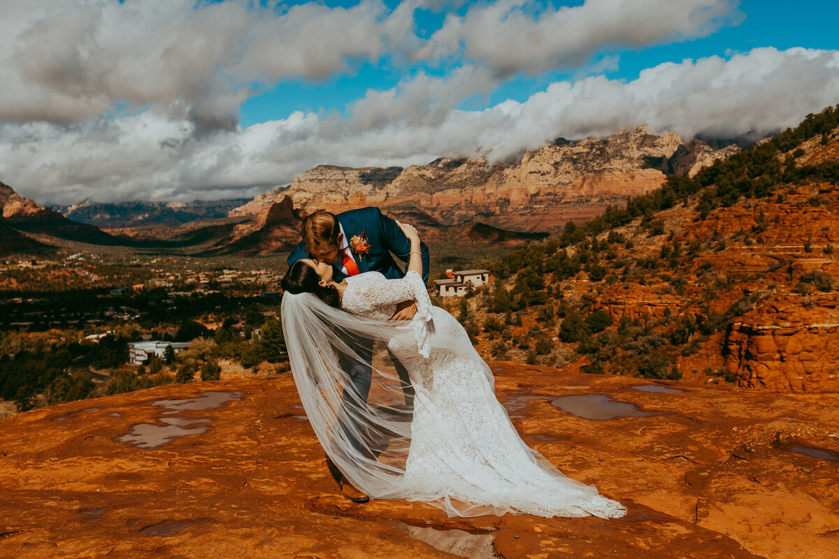 couple on red rocks kiss in bridal attire