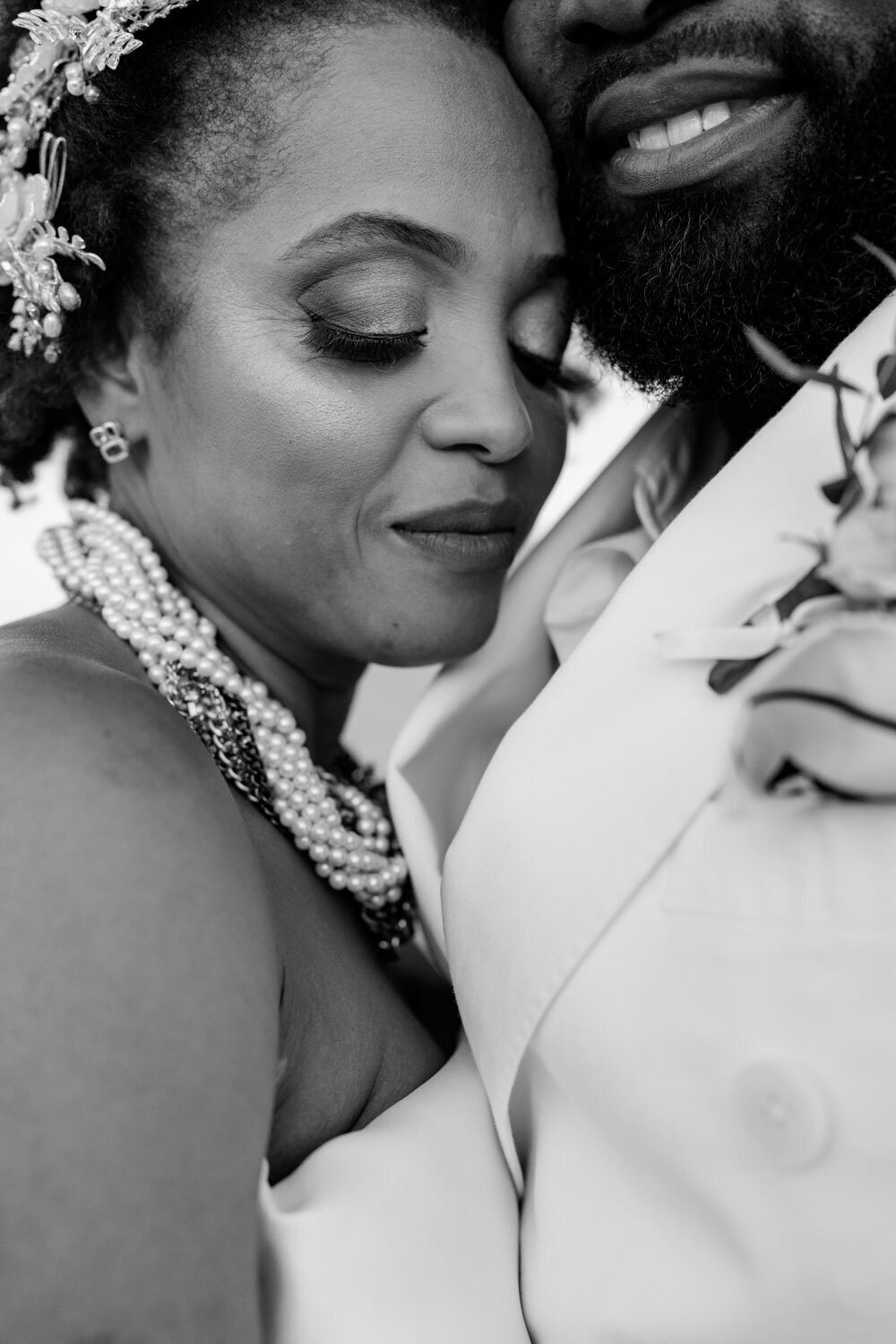 Close-up of bride and groom embracing, both smiling softly