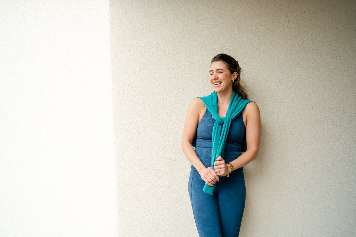 a woman laughing holding the sleeves of her jumper