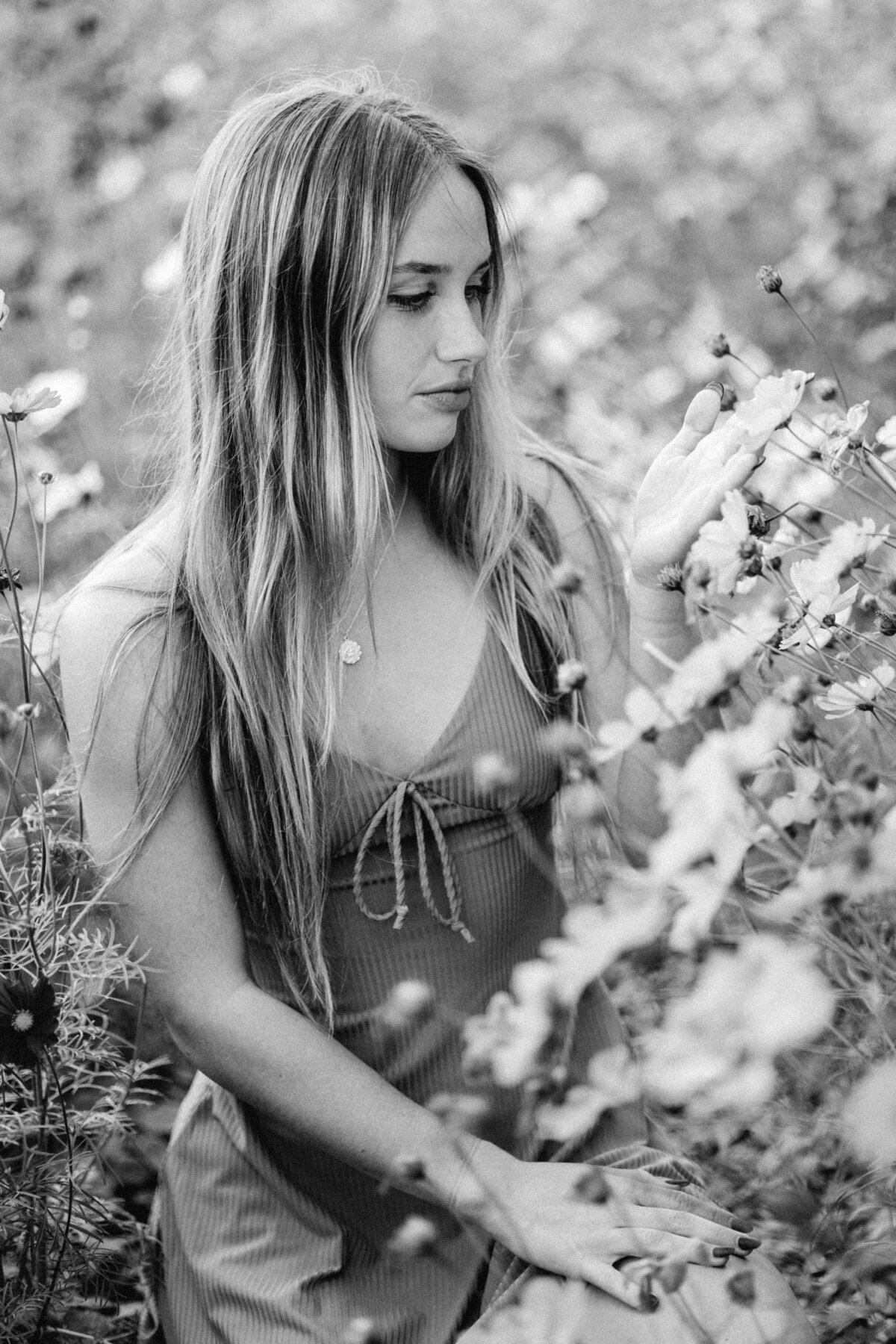 Woman sitting in grass surrounded by flowers, dreamy outdoor portrait in Wilmington
