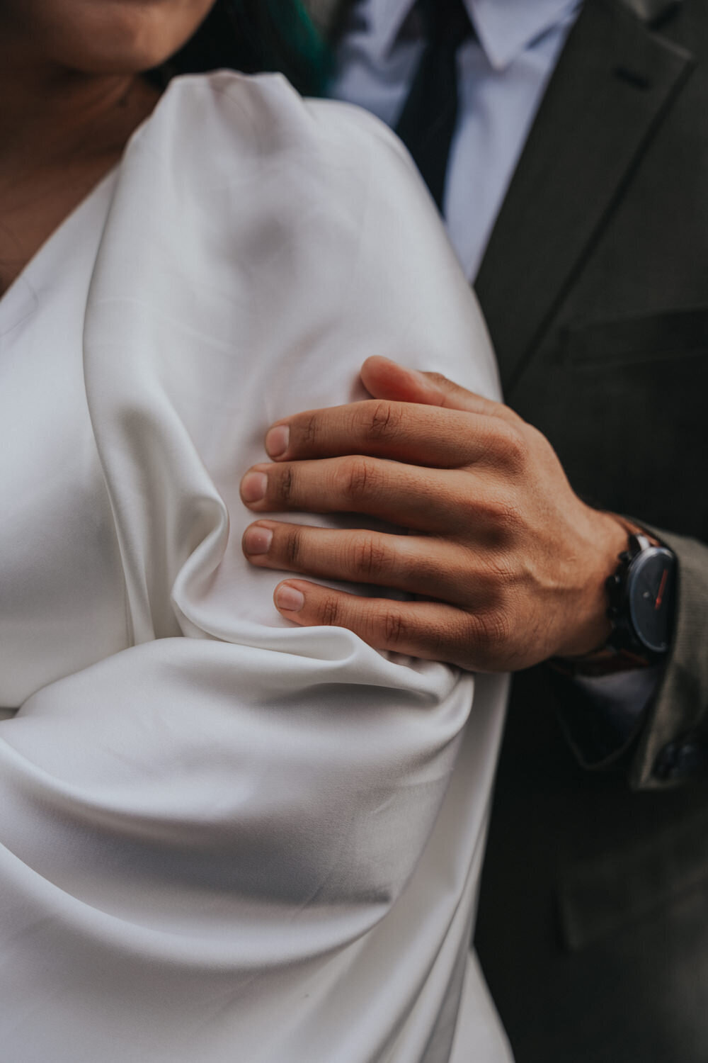 Husband rests his hand on his wife's arm as they embrace 