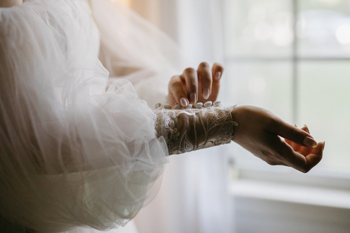 bride carefully putting on her wedding dress