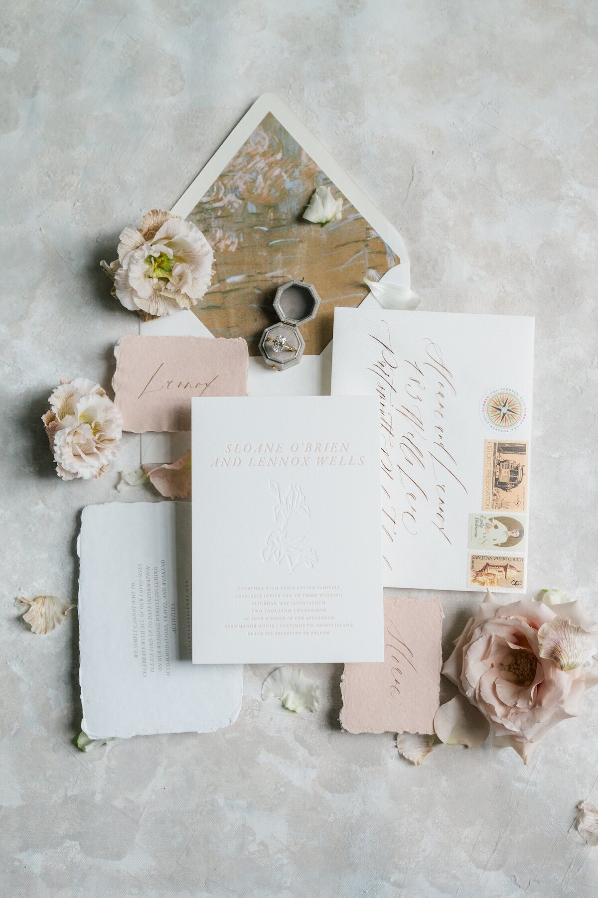 A luxe wedding flat lay of an invitation suit, name tags, and rings. 