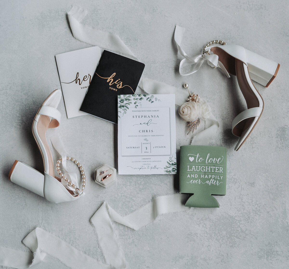 Flat lay of wedding day details including bride’s shoes, vow booklets, invitation suite, and jewelry on a soft gray background. Gentry Farm, Danville Virginia.
