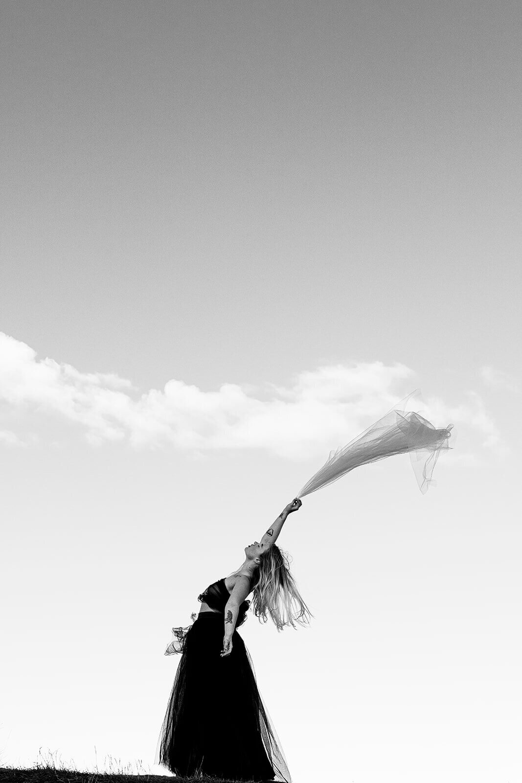 Romantic wedding shoot, Fine art shot of a veil being blown in the wind as the bride leans back with her arms in the air.