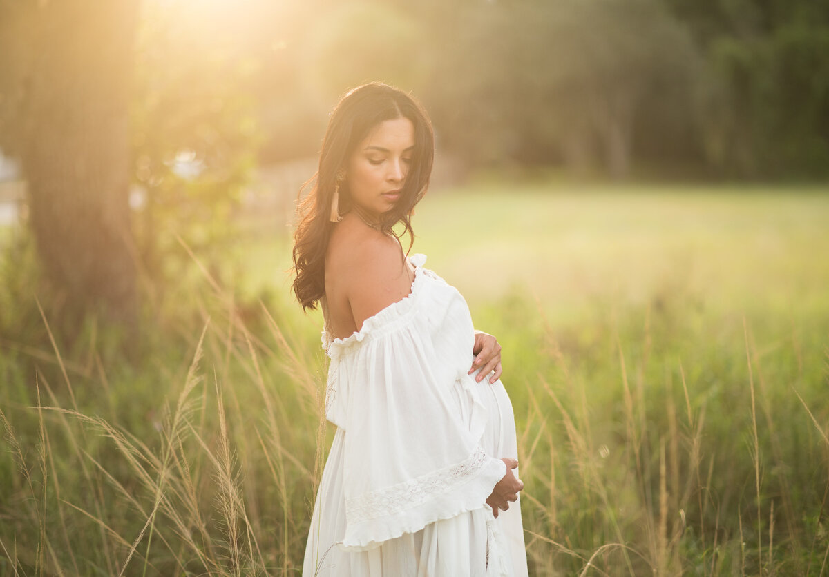 a outdoor maternity session of a women with a white dress on