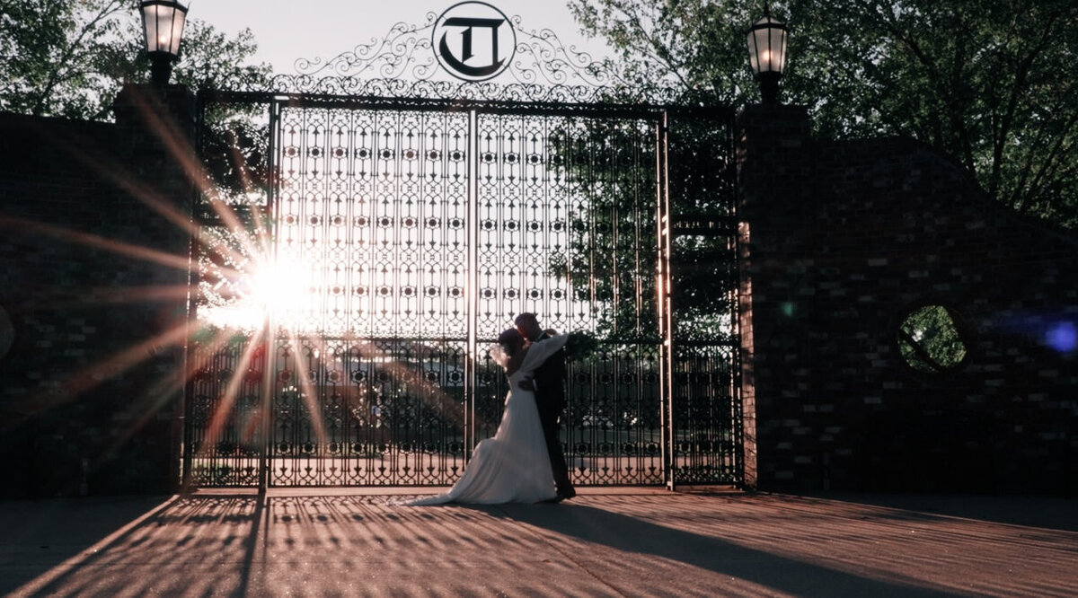 A wedding couple dancing in front of a grand gate 