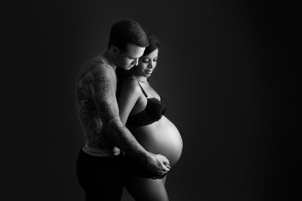 Maternity photo of a couple looking down at the pregnant belly