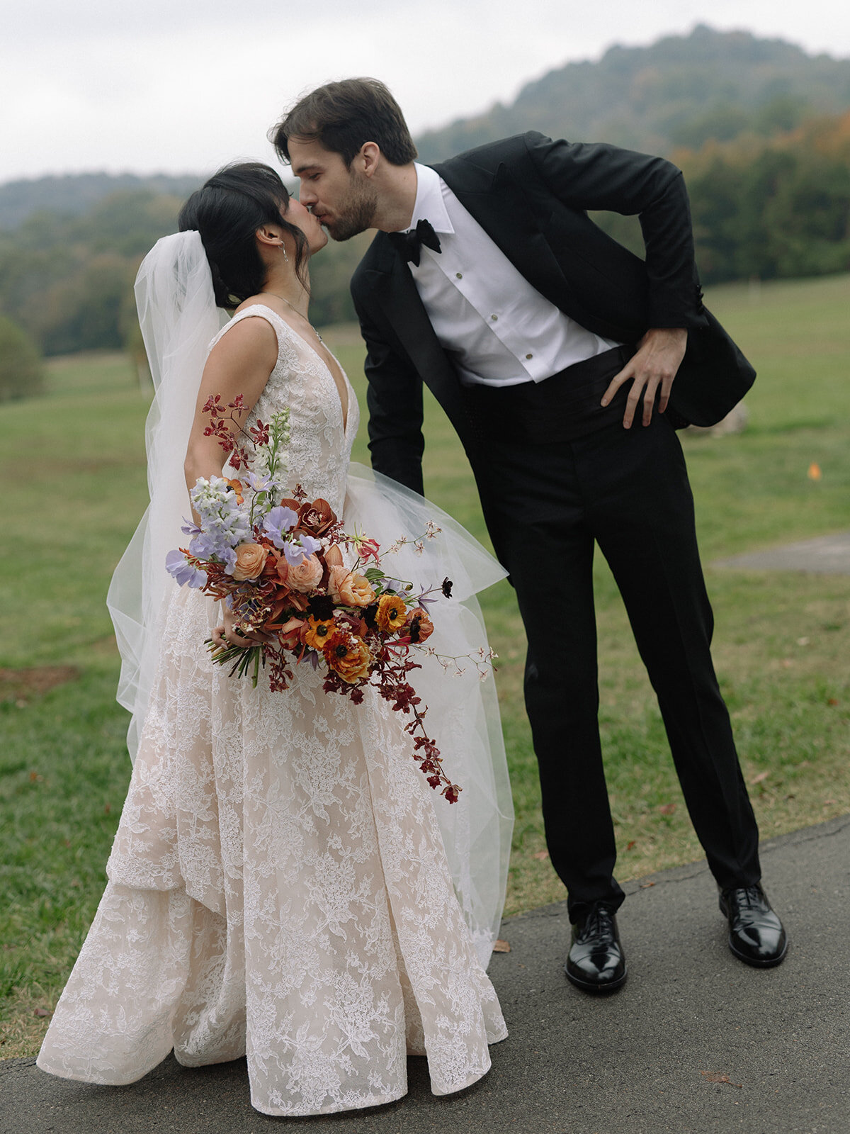 Organic artistic bridal bouquet with delicate blooms and texture. Fall bridal bouquet for private home wedding featuring orchids, ranunculus, and sweet peas. Textural bridal bouquet in a tasteful fall pallet of copper, lavender, gold, and ruby. Private property autumnal wedding in the hills of Tennessee. Design by Rosemary & Finch Floral Design in Nashville, TN. 