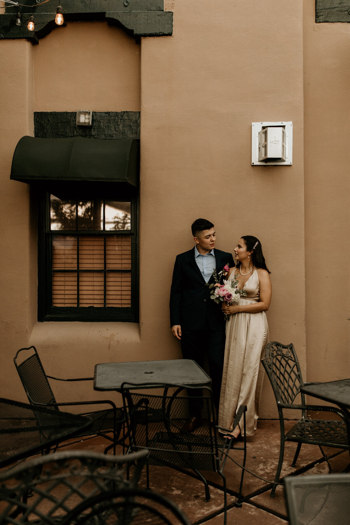 new bride and groom standing against an adobe wall in Albuquerque