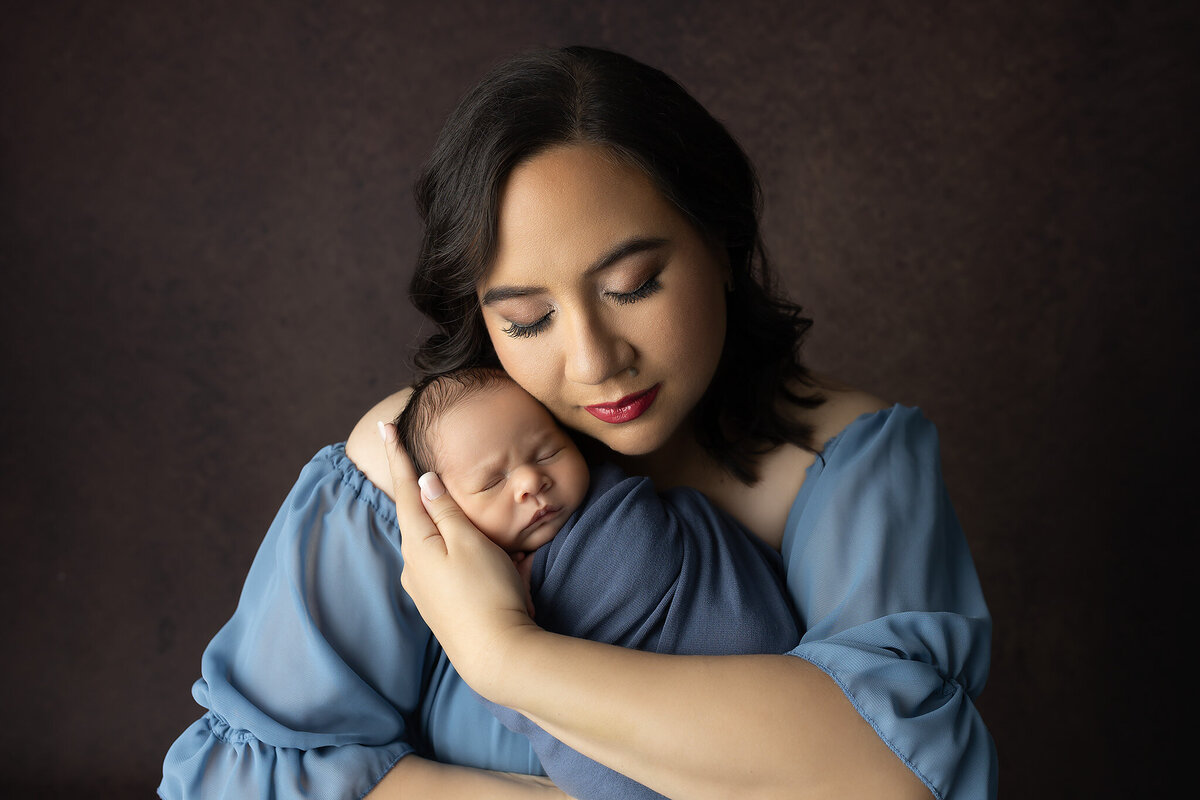 Tender moment of a mother with eyes closed as she cradles her sleeping baby, captured in a DFW newborn photography session.