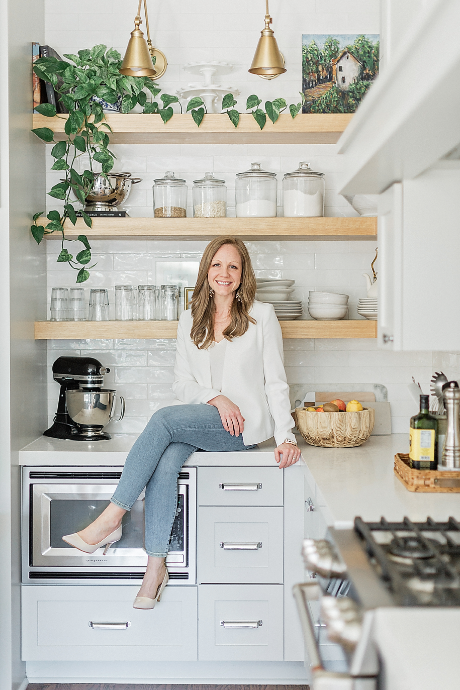 Professional headshot photo of a Dallas Texas business woman posing on a counter of a beautifully designed kitchen as she smiles at the camera for her branding/headshot session.