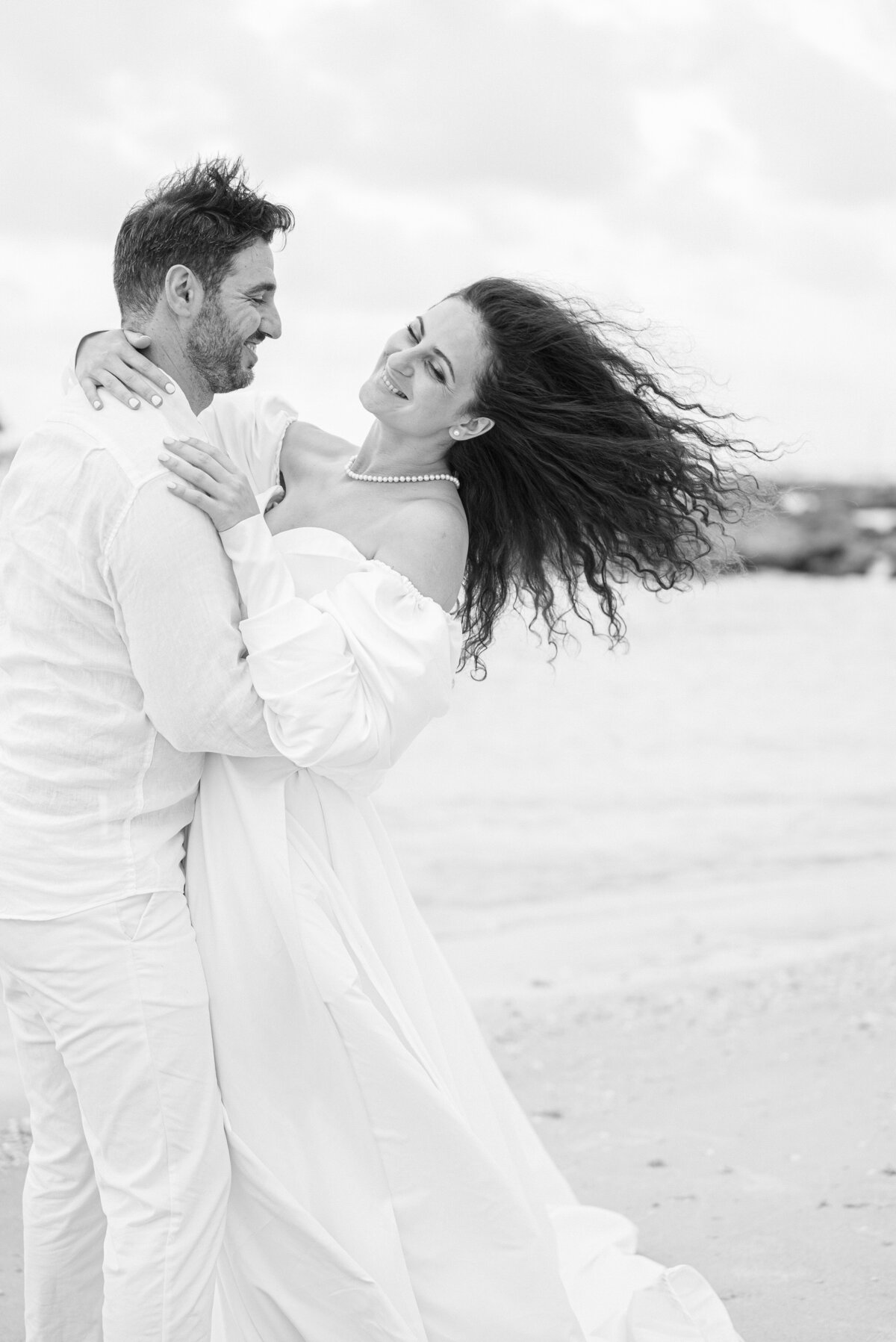 Bride laughing with her husband on the beach