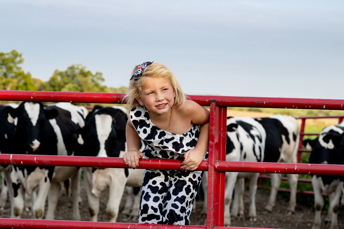 A little girl looks up as she sticks her head through a cow gate