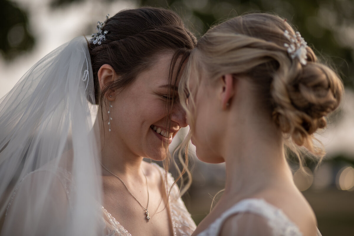 two brides smiling and resting their foreheads together