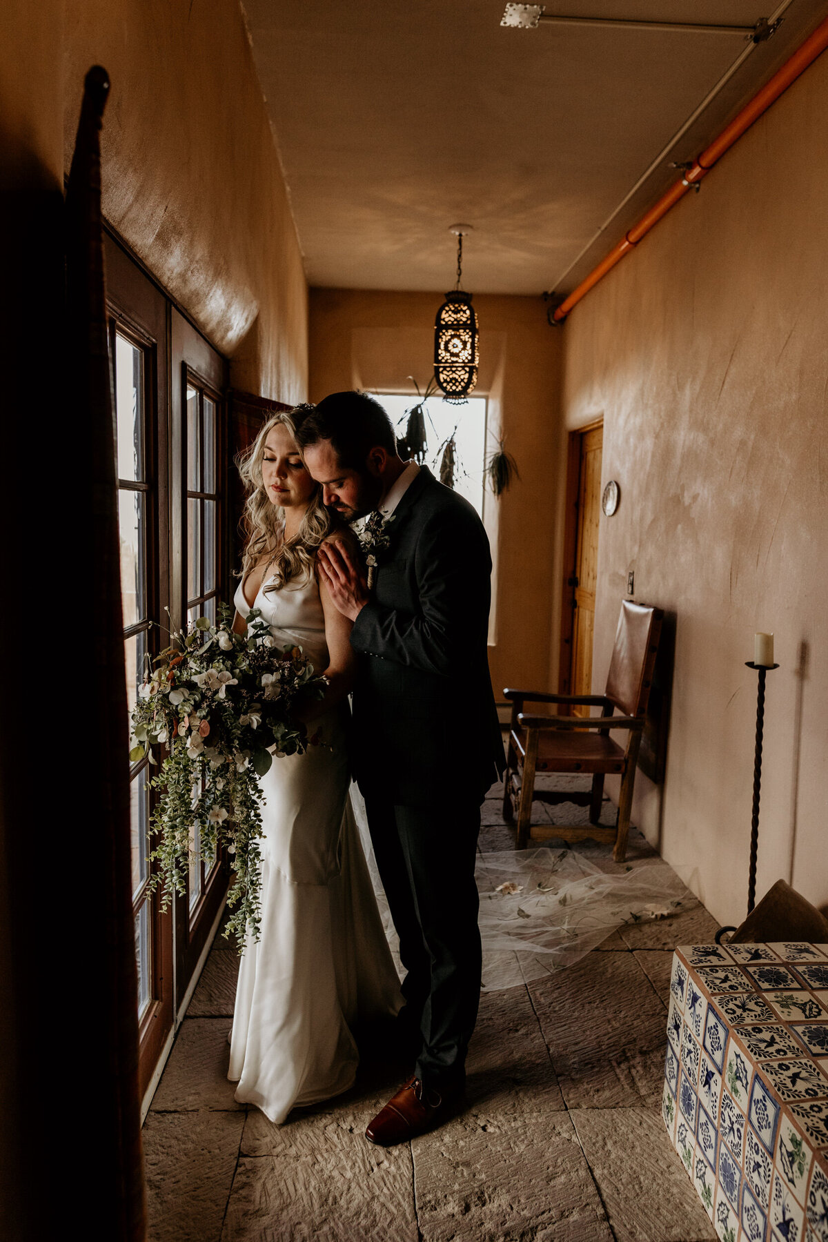 groom holding bride from behind and kissing her shoulder