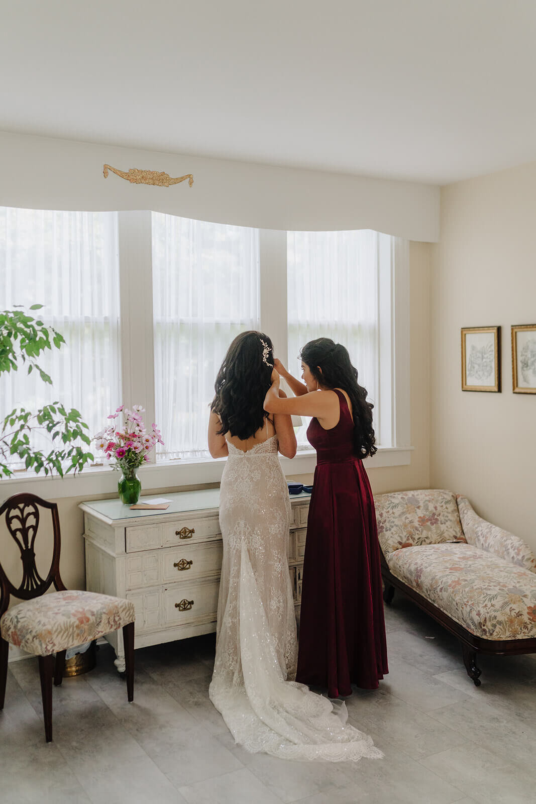 Bridesmaid helping bride fix hair at Finger Lakes wedding, NY