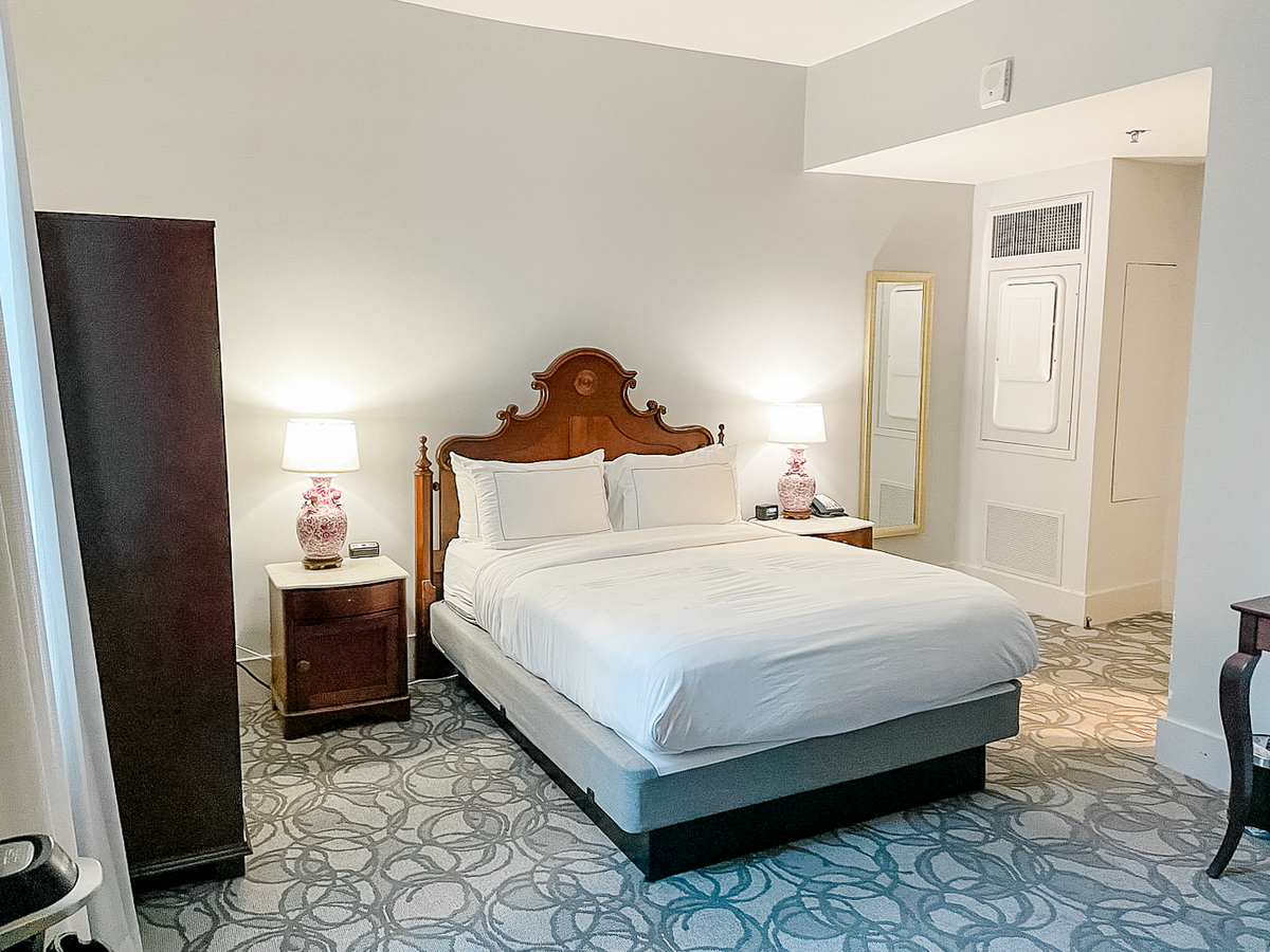 Boutique hotel guest room with ornate head board on queen size bed