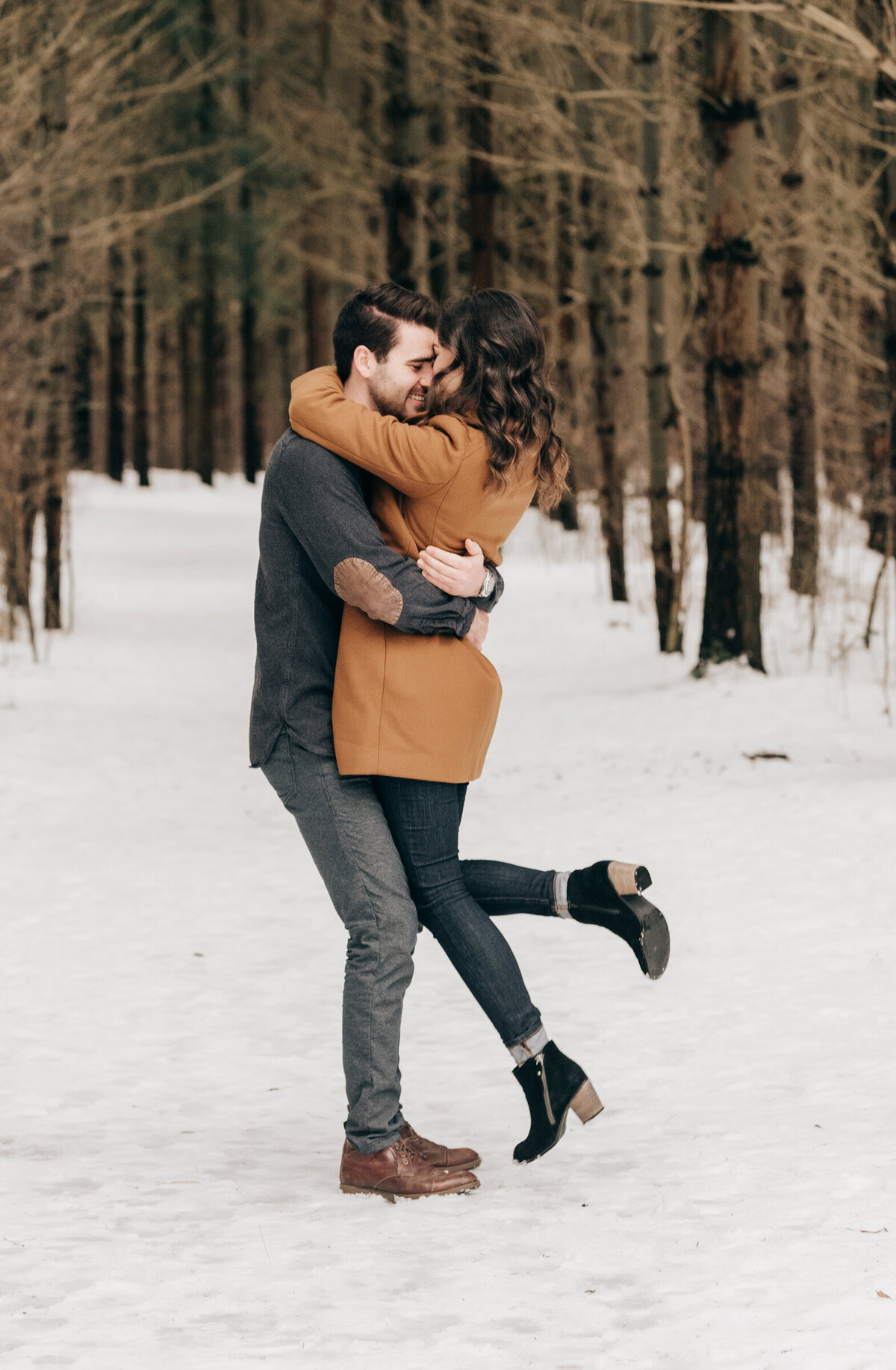 Couple posing in a forest for their Winter engagement session at Fanshawe Conservation Area in London Ontario