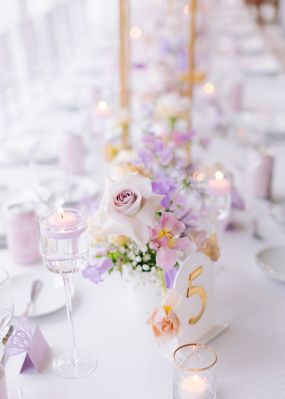 A beautifully styled reception table with tall golden centerpieces, pastel florals, and elegant place settings