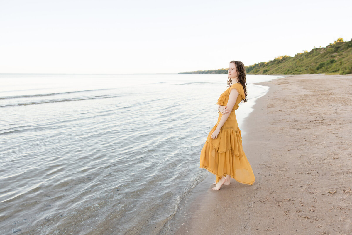 Senior girl on the beach looking out toward a lake