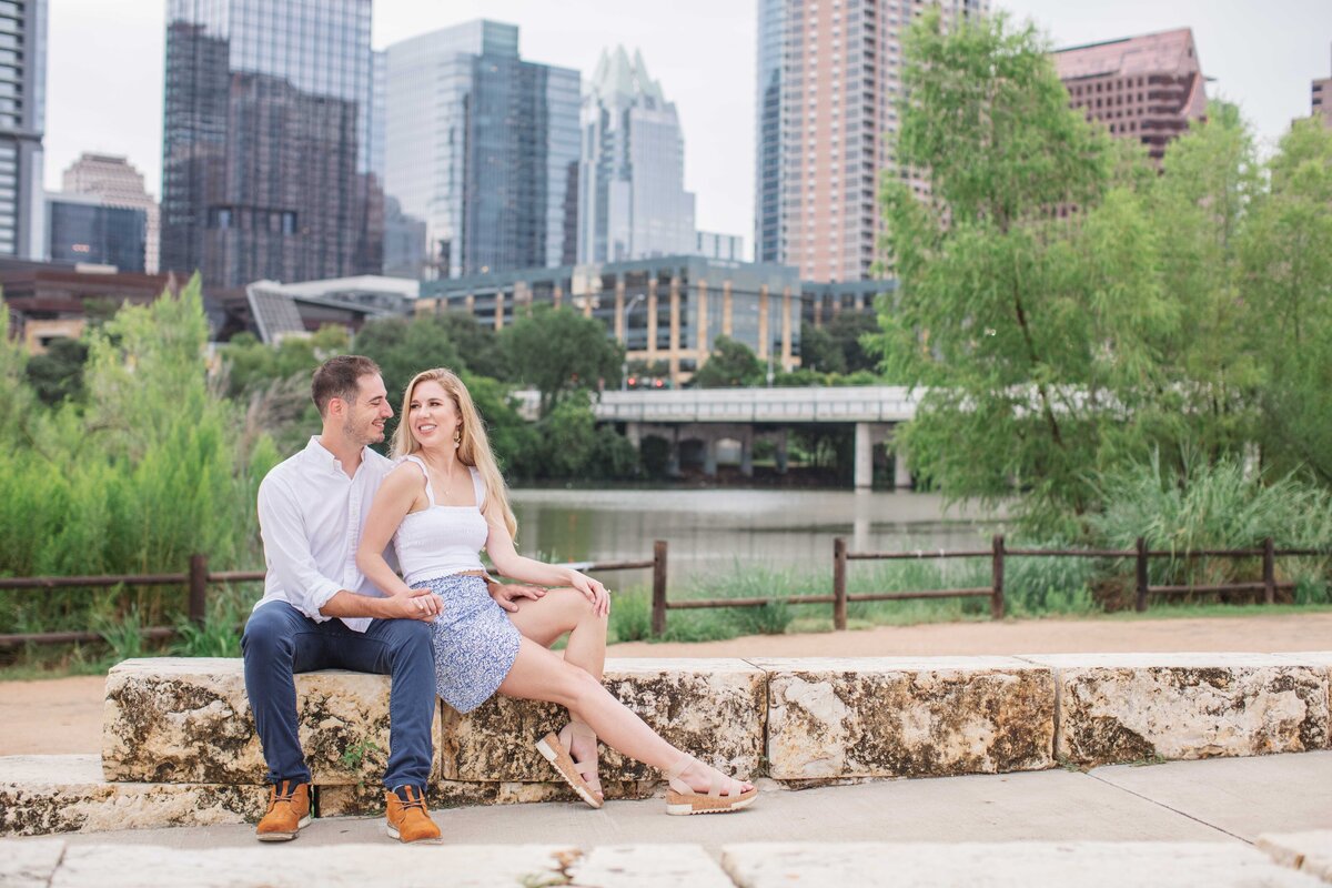 wedding engagement session with couple sitting before Austin skyline at Zilker Park by Firefly Photography
