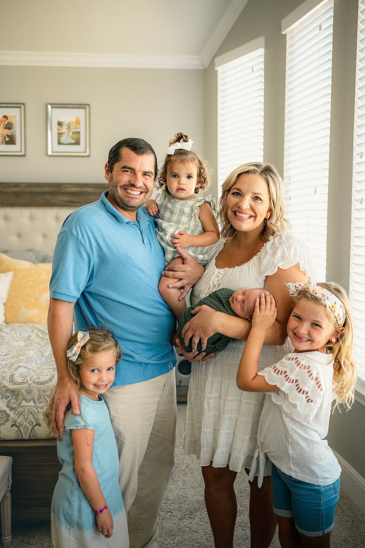 Family of 5 holding new baby brother smiling at camera by Houston Newborn Photographer